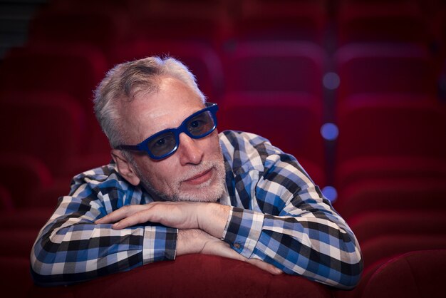 Hombre mayor viendo película en cine