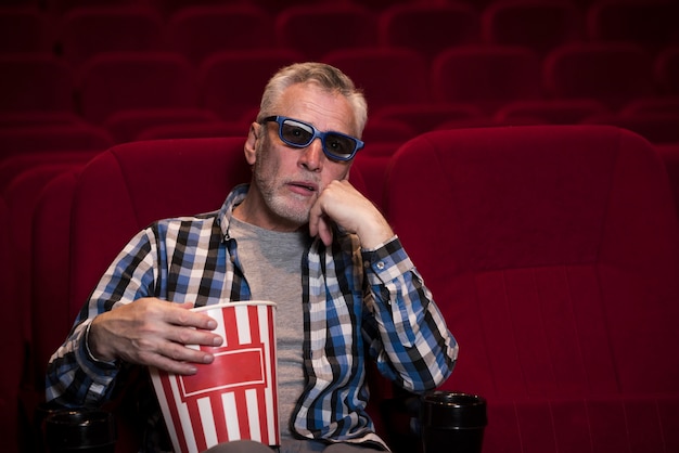 Hombre mayor viendo película en cine