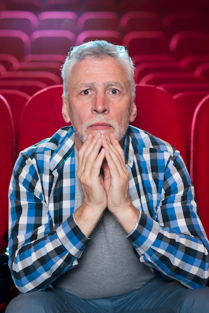 Hombre mayor viendo película en cine