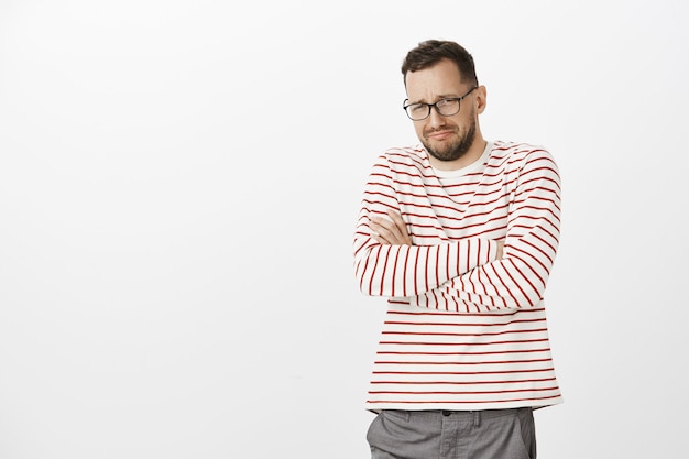 El hombre me dejó en nuestro aniversario. Retrato de modelo de hombre caucásico llorando miserable en gafas, cruzando las manos sobre el pecho y lloriqueando