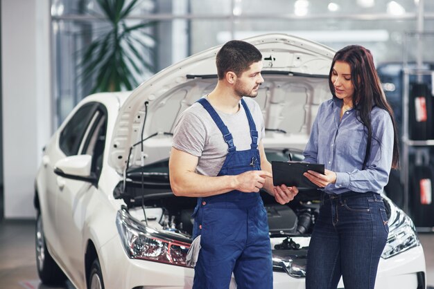 Un hombre mecánico y una clienta discutiendo reparaciones hechas a su vehículo