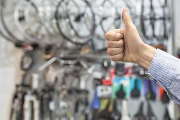 Hombre mecánico gesticular pulgares arriba en el taller de bicicletas