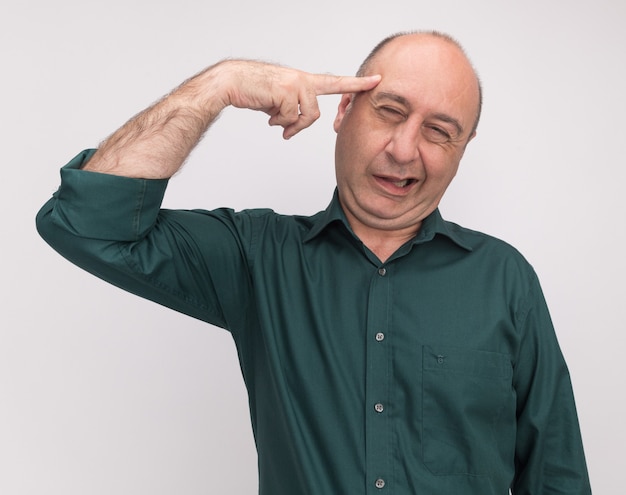 Foto gratuita hombre de mediana edad alegre con camiseta verde poniendo el dedo en la sien aislado en la pared blanca