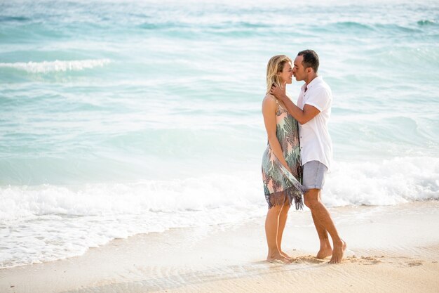 Hombre de mediana edad besando esposa en la playa soleada