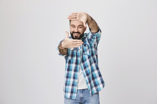 Hombre de mediana edad creativo captura el momento, muestra el gesto de los marcos de la mano