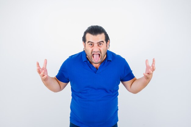 Hombre de mediana edad manteniendo las manos de manera agresiva mientras saca la lengua