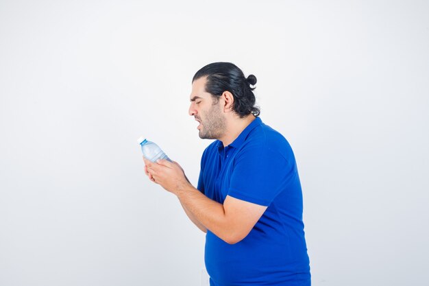 Hombre de mediana edad mirando la botella de agua con enojo