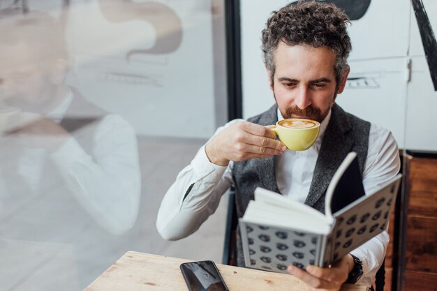 Hombre de mediana edad de nacionalidad judía pasa la tarde o la mañana en una cafetería de moda o hipster