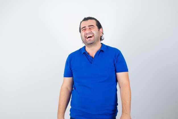 Hombre de mediana edad riendo en camiseta azul, de aspecto alegre