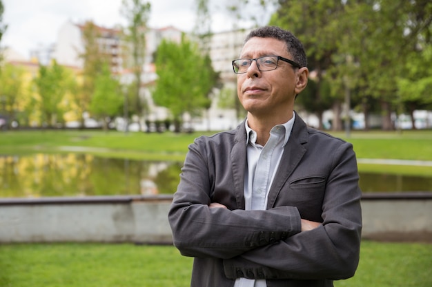 Hombre de mediana edad soñador que se coloca en parque de la ciudad