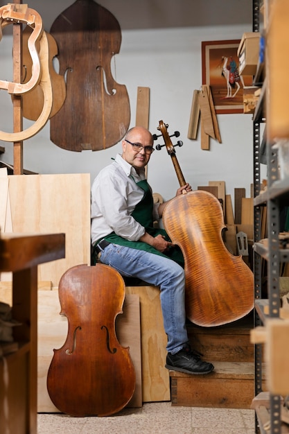 Foto gratuita hombre de mediana edad en su taller de instrumentos