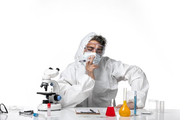 Hombre médico en traje de protección con máscara estéril sosteniendo la inyección en blanco