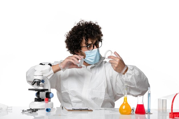 Hombre médico en traje de protección y máscara sosteniendo frascos en blanco