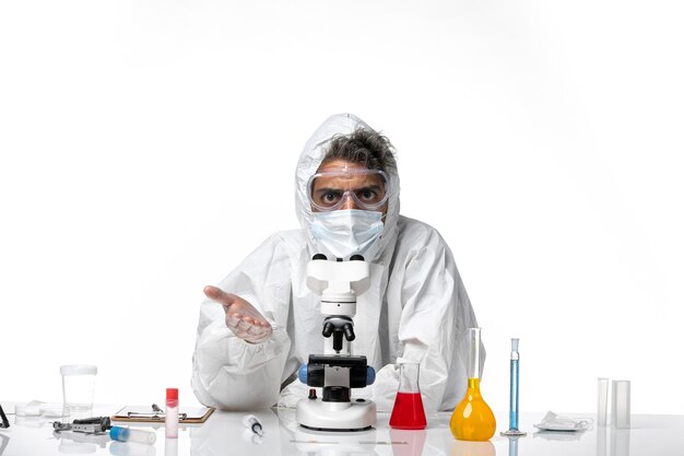 Hombre médico en traje de protección y máscara con su microscopio en blanco
