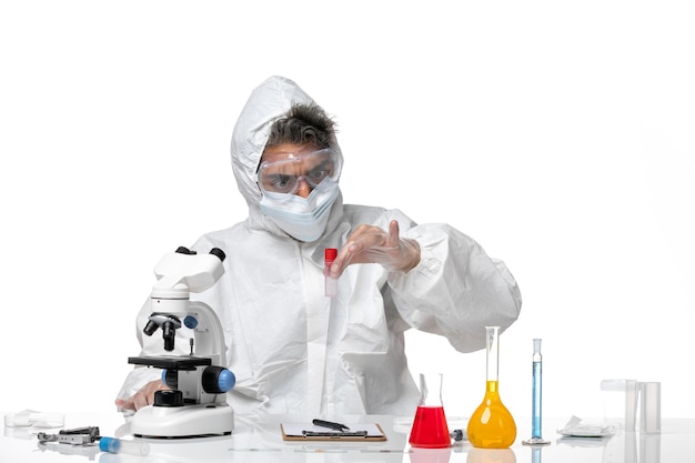 Hombre médico en traje de protección y con mascarilla sosteniendo el matraz en blanco