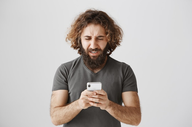 Hombre del Medio Oriente frustrado y molesto mirando el teléfono angustiado