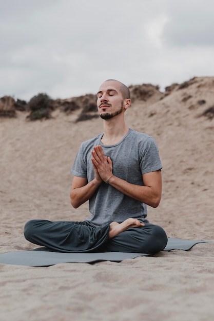 Foto gratuita hombre meditando al aire libre mientras hace yoga