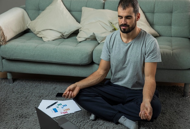 Hombre meditando junto al sofá antes de comenzar a trabajar