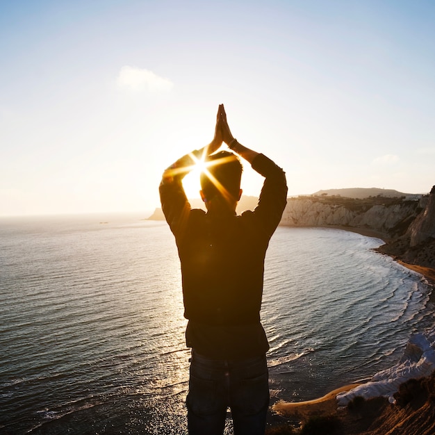 Foto gratuita hombre meditando con las manos en el acantilado