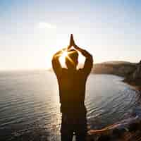 Foto gratuita hombre meditando con las manos en el acantilado