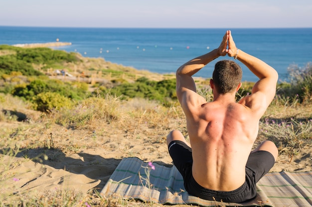 Foto gratuita hombre meditando mirando hacia el mar