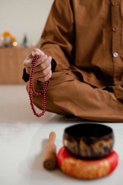 Foto gratuita hombre meditando con perlas junto al cuenco tibetano