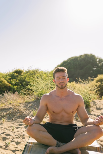 Foto gratuita hombre meditando por la playa