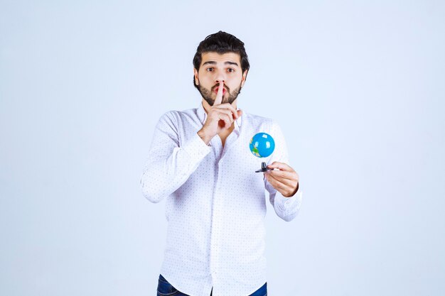 Hombre con un mini globo pidiendo silencio