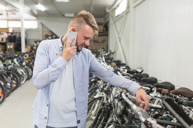 Hombre mirando bicicleta mientras habla por teléfono móvil en la tienda
