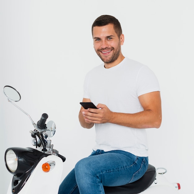 Hombre mirando a cámara y escribiendo en su teléfono móvil