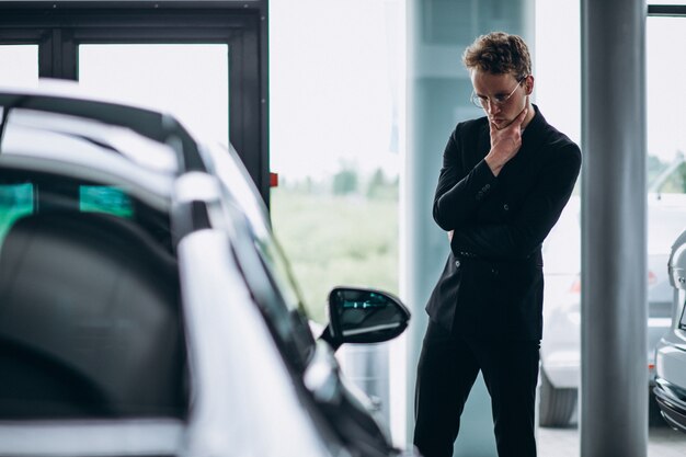 Hombre mirando un carro y pensando en una compra.