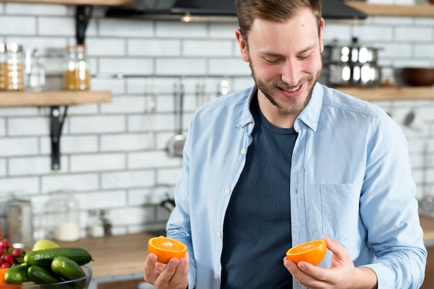 Hombre mirando dos rodajas de naranja en la cocina