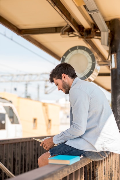 Foto gratuita hombre mirando en un mapa y esperando el tren