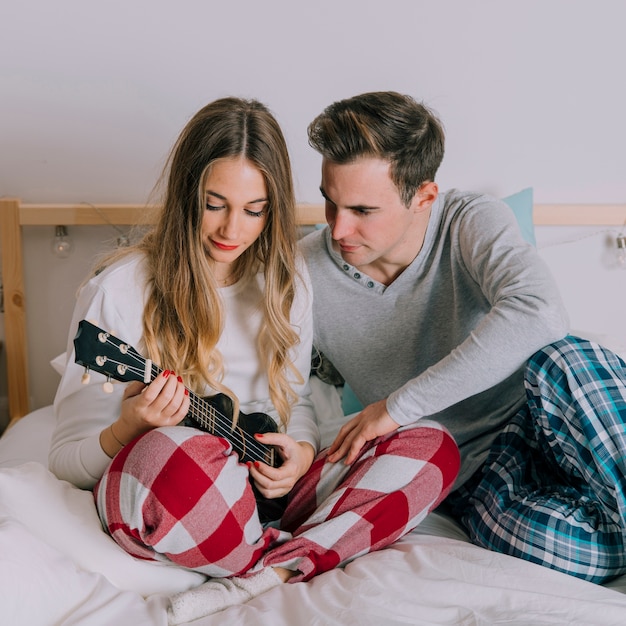 Hombre mirando a la mujer jugando al ukelele