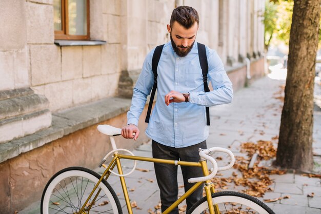 Hombre mirando reloj cerca de bicicleta