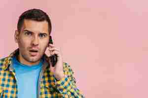 Foto gratuita hombre mirando sorprendido mientras habla por teléfono