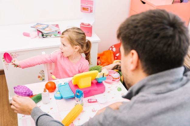 Hombre mirando a su hija jugando con juguetes