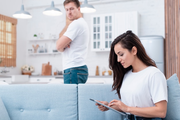 Hombre mirando a su novia que está mirando en la tableta