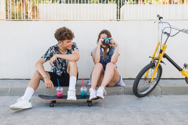 Hombre mirando a su novia tomando una fotografía con cámara