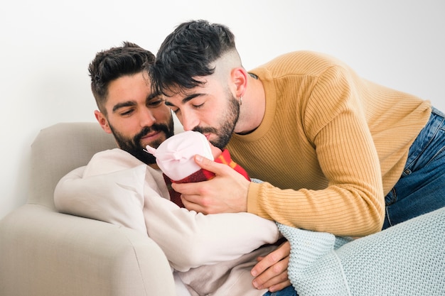 Hombre mirando a su novio besando a su bebé durmiendo