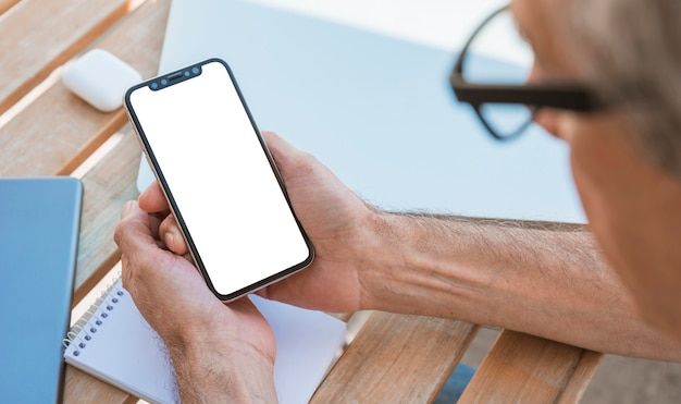 Foto gratuita hombre mirando teléfono inteligente con pantalla en blanco en blanco