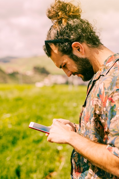 Hombre mirando el teléfono móvil en el campo