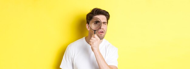 Hombre mirando a través de una lupa con mirada seria y pensativa buscando o investigando sta
