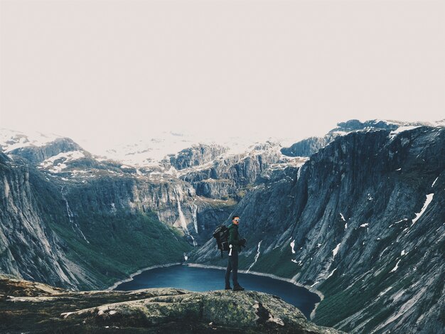 El hombre con una mochila admira el paisaje de montaña magnífico