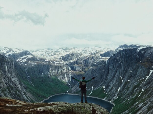 El hombre con una mochila admira el paisaje de montaña magnífico