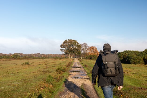 Hombre con mochila caminando por un sendero en un campo