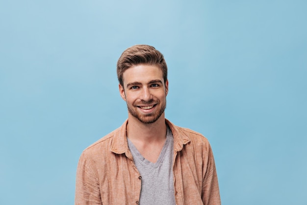 Hombre de moda de buen humor con peinado corto en ropa fresca sonriendo y mirando a la cámara en un fondo aislado