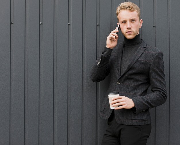 Hombre de moda con café hablando por teléfono