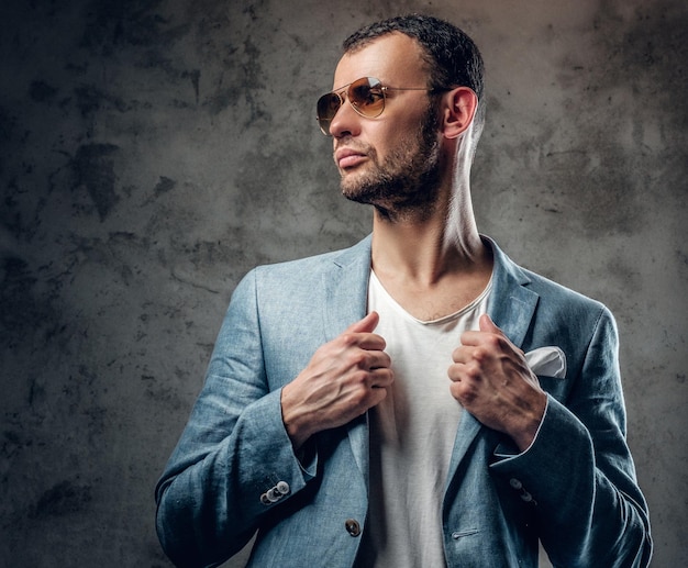 Foto gratuita hombre de moda con chaqueta azul y gafas de sol posando en un estudio.