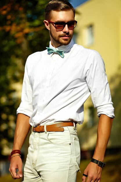 Hombre modelo guapo hipster en ropa de verano elegante posando en gafas de sol